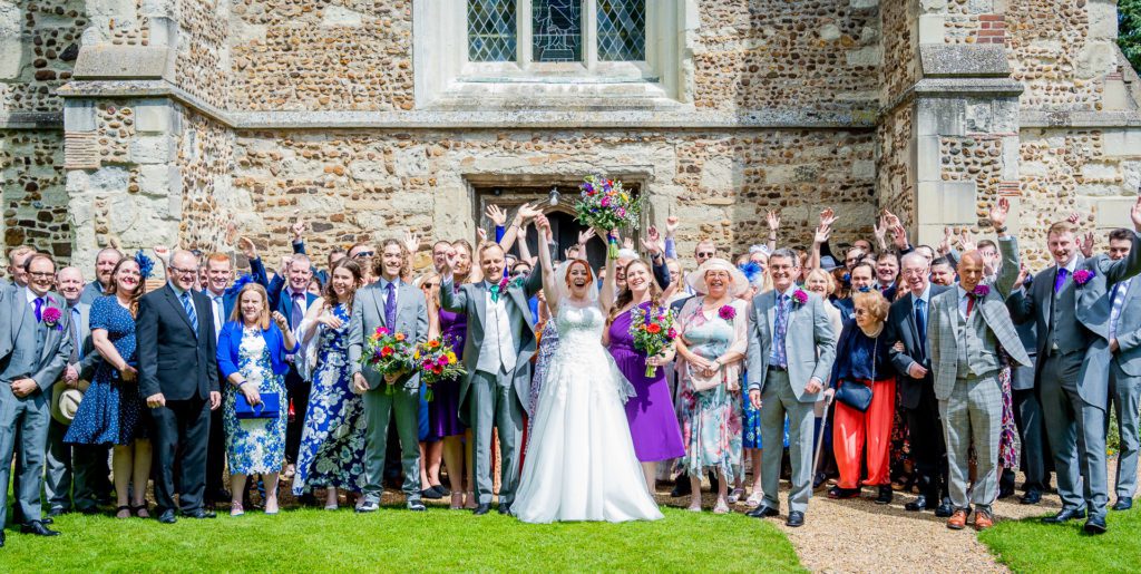 Bride, groom and their wedding guests standing out side the Church in Henlow