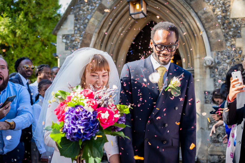 Happy couple, just married with confetti, outside their church in Watford