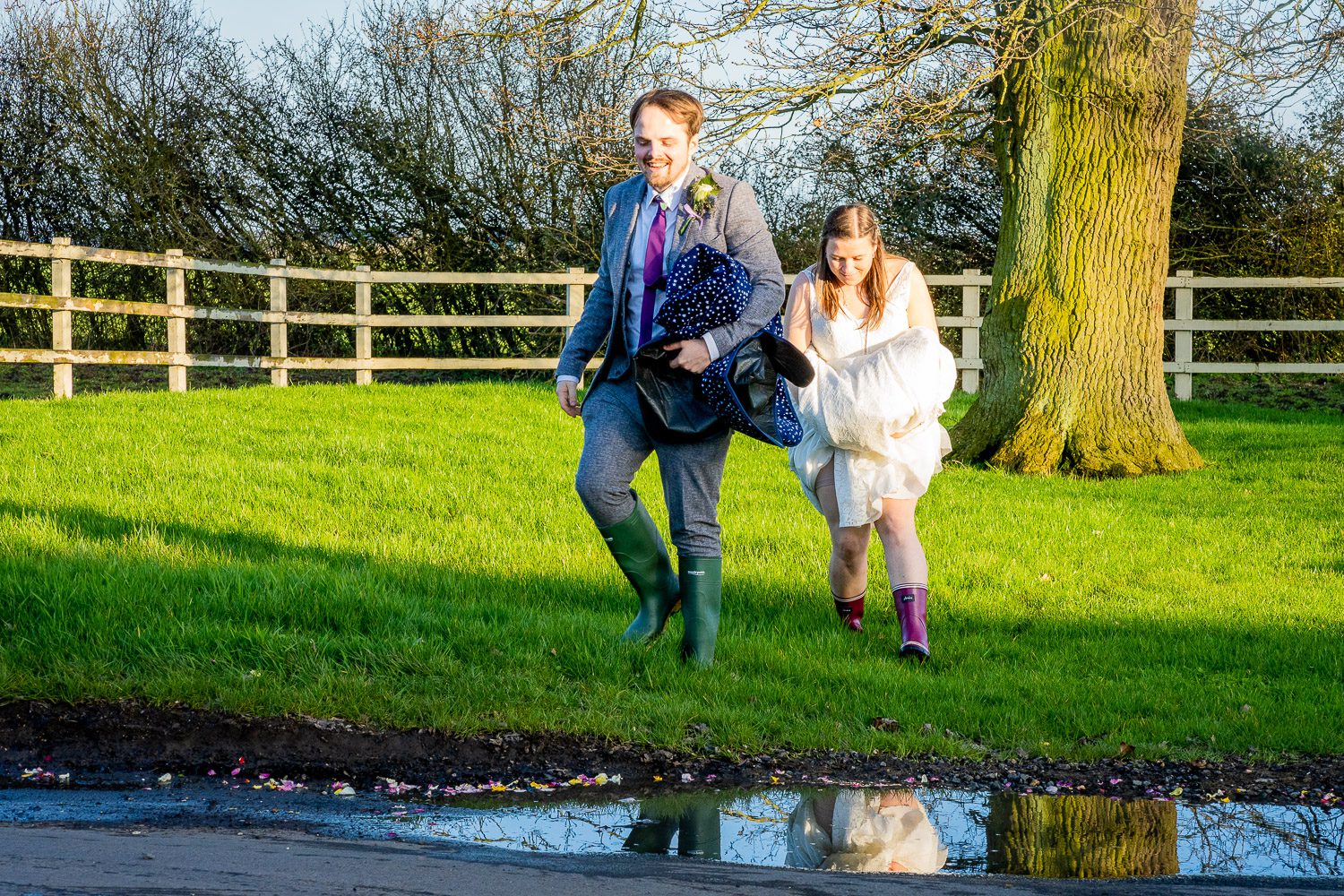 Relaxed wedding photography captured a bride and groom running in their wellies at Milling Barn, a Hertfordshire wedding venue