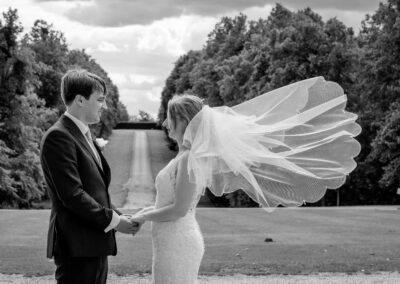 Sarah and Michael at Braxted Park, Essex. A black and white image with the bride's veil blowing n the wind