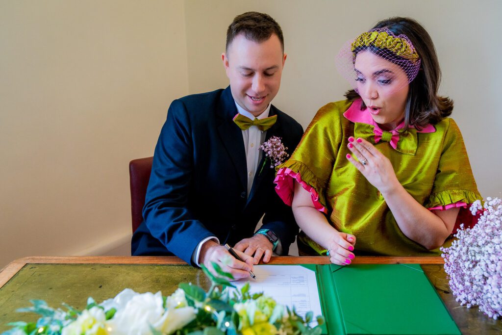 Bride and Groom signing the wedding register at Hertford registry office just after their wedding ceremony. Taken by Tim Payne Photography