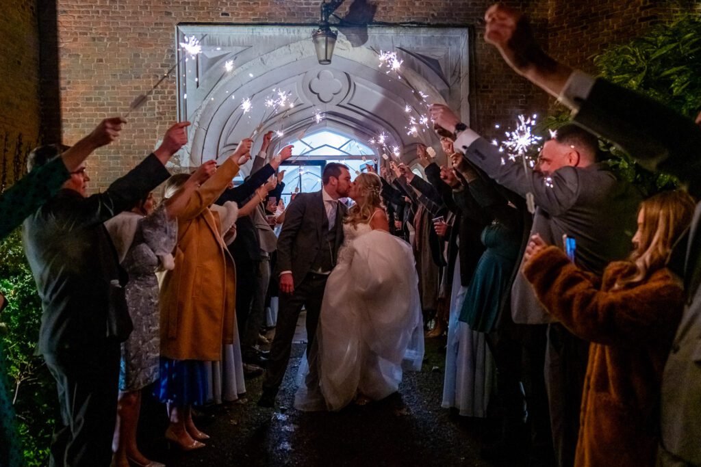 Bride and Groom walking through a sparkler arch at Hertford Castle. Taken by Tim Payne Photography
