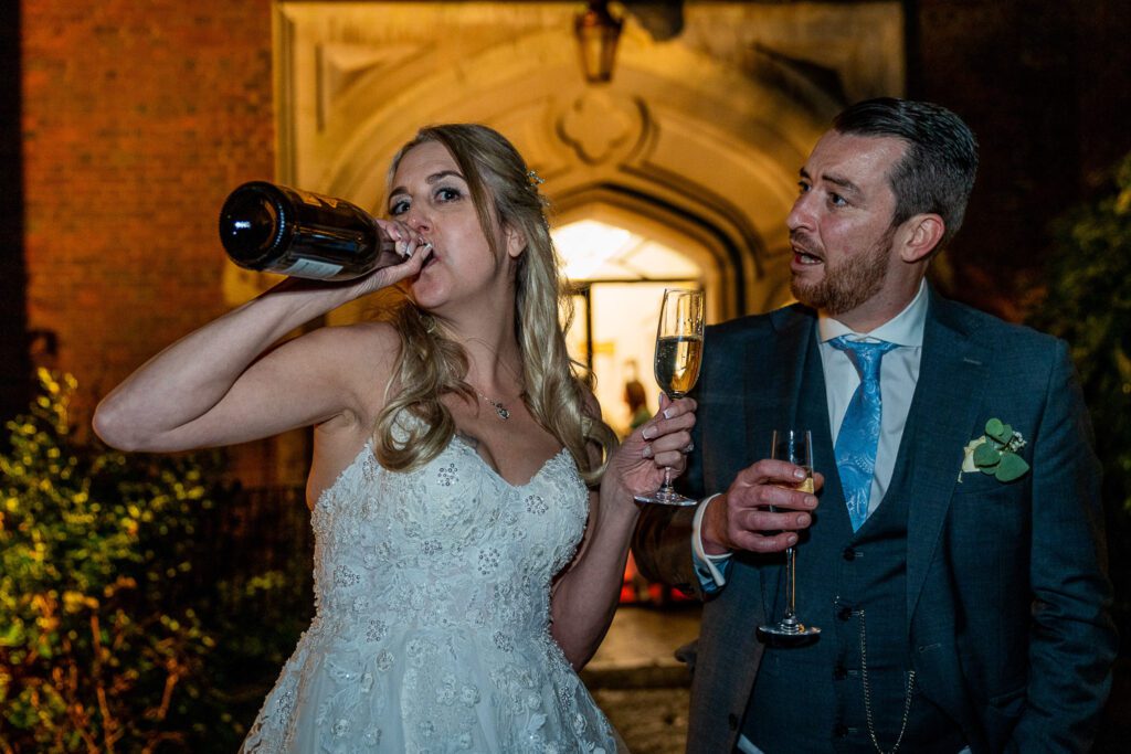 Bride and Groom celebrating with a bottle of champagne in the evening at Hertford Castle