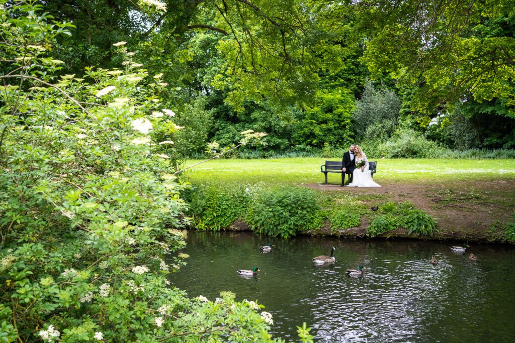 A newly married couple sitting by the river in the grounds of Hertford Castle. Taken by Tim Payne Photography
