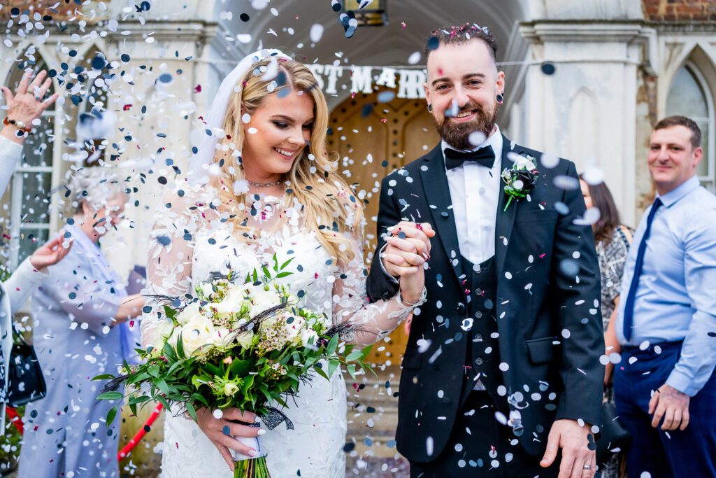 A newly married couple having their confetti throw at Hertford Castle . Taken by Tim Payne Photography, a Hertford wedding photoographer