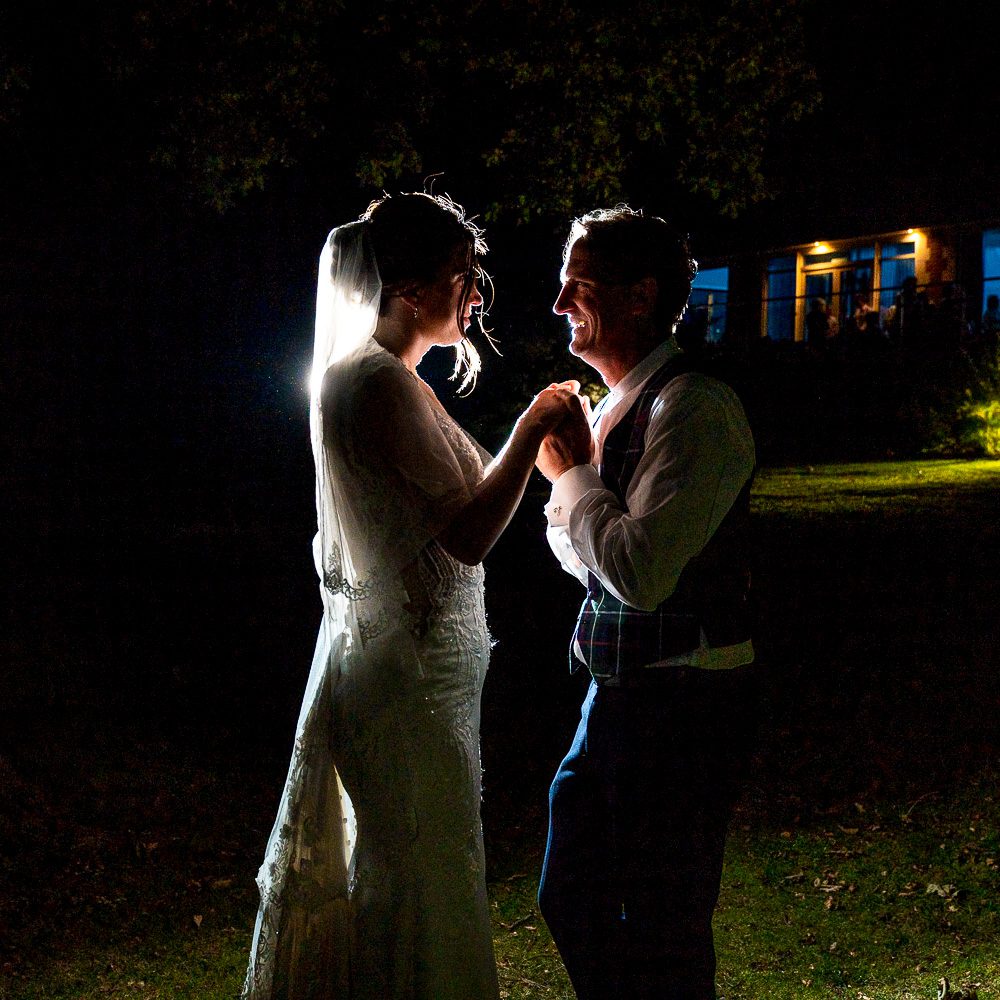 Cheap Wedding Photographers -A beautifully lit night-time image of a bride and groom dancing outside their venue
