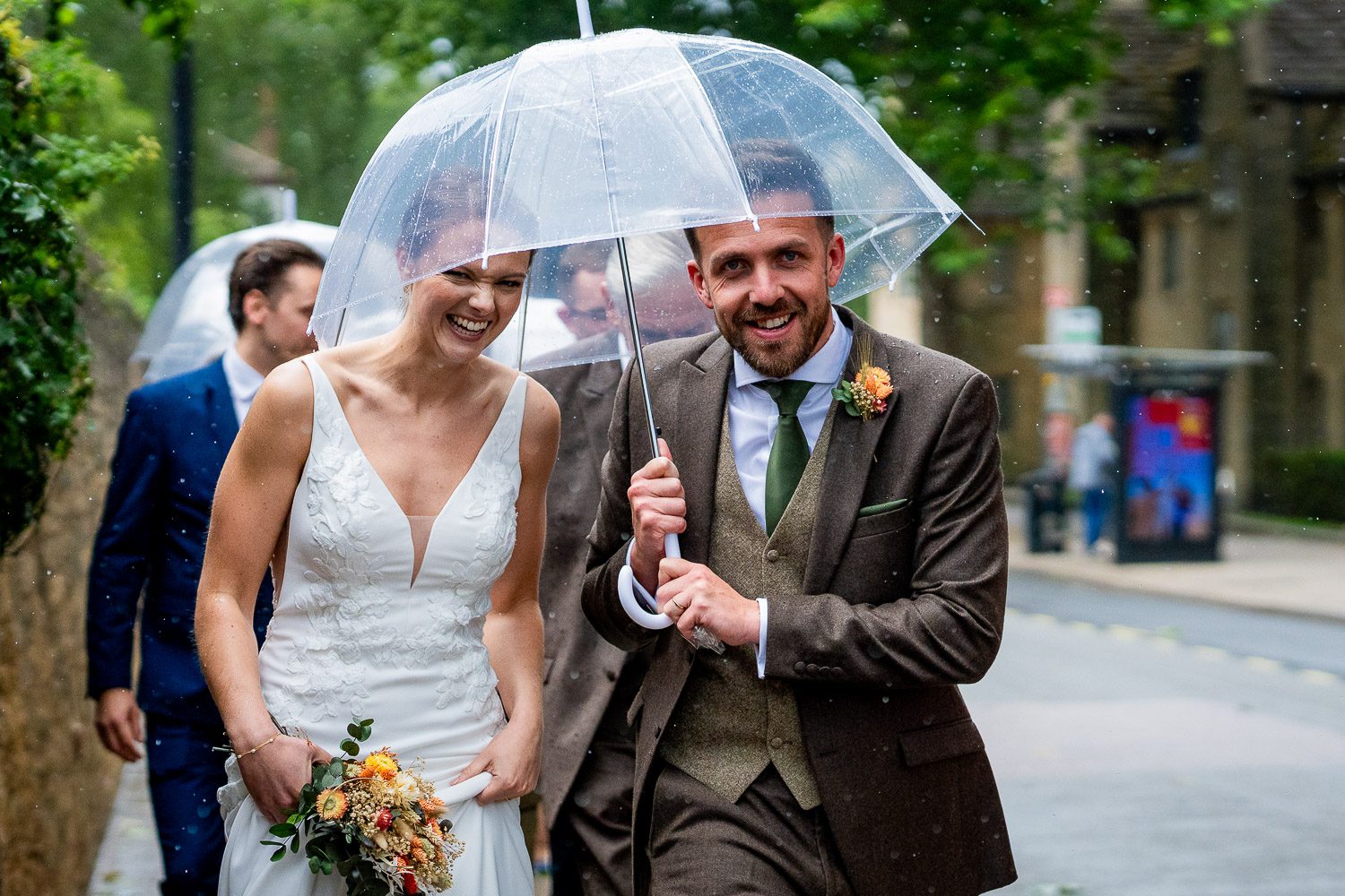 award-winning wedding photographer. A bride and groom walking down the street laughing with a clear umbrella over their heads