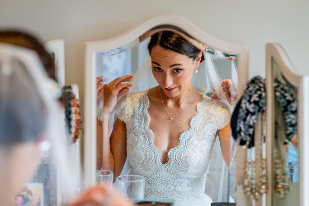 Bride putting on her veil just before she sees her father for the first time on her wedding day. Tim Payne Photography a Hertford wedding photographer.