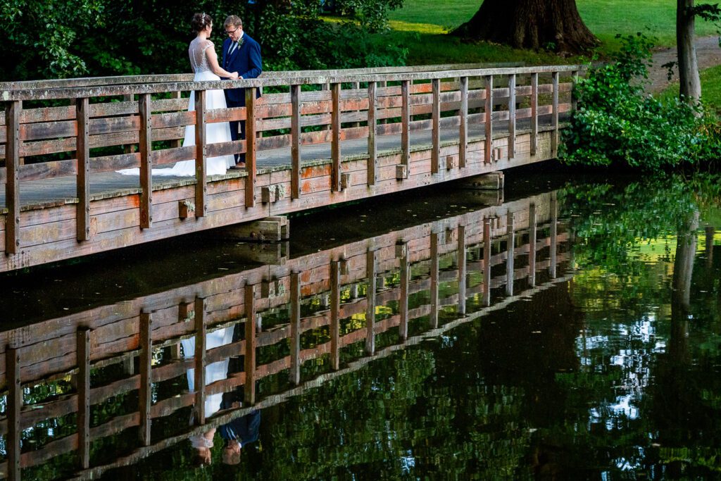 Bride and groom reflected in a lake at Essendon country club. Tim Payne photography, a Hertfordshire based wedding photographer