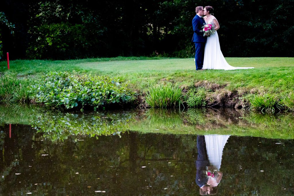 Bride and groom reflected in a lake at Essendon country club. Tim Payne photography, a Hertfordshire based wedding photographer