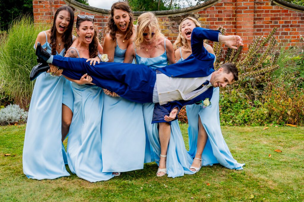 Groom being dropped by the bridesmaids when they try to hold him in their arms.Tim Payne Photography a Hertford wedding photographer