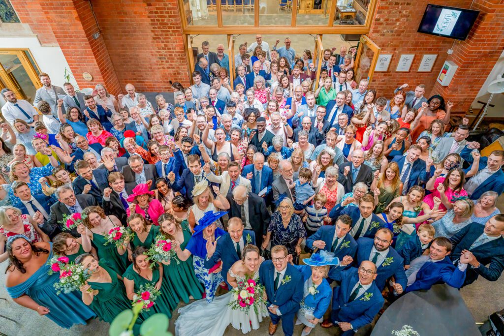 Group photo of wedding guests at a large wedding, taken from a balcony inside the church. Tim Payne photography, a Hertford based wedding photographer