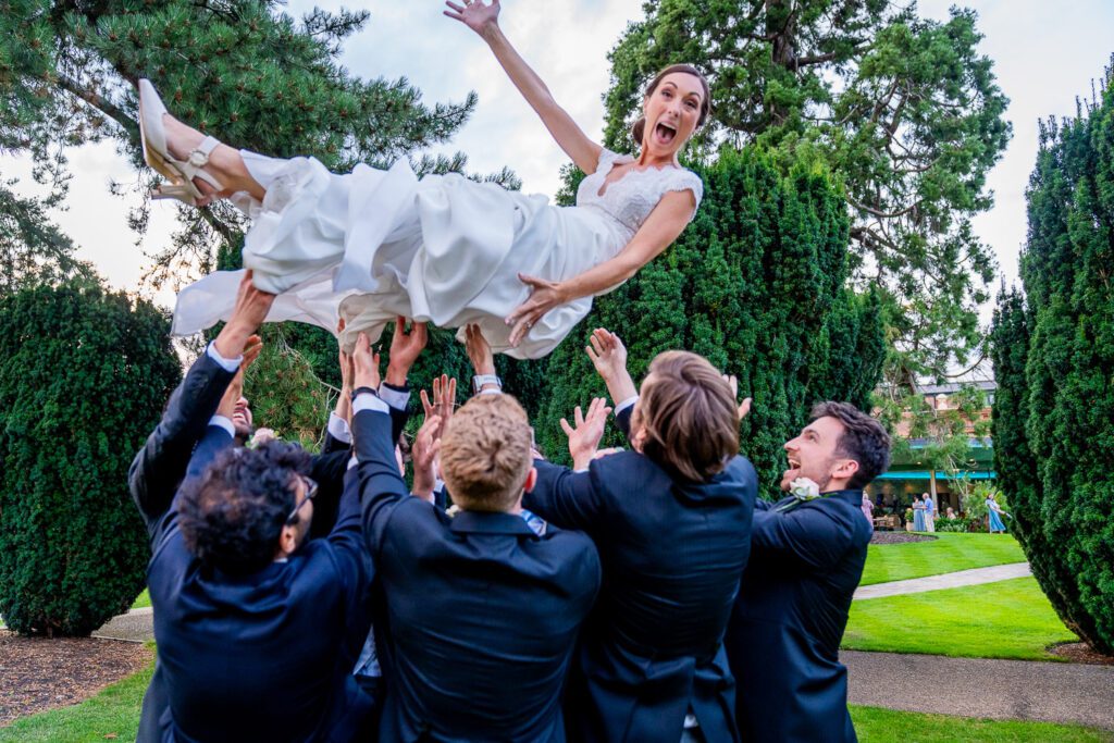 Bride being thrown in the air by the groomsmen at the Grove Hotel, Watford. Tim Payne Photography, a Hertfordshire wedding photographer.