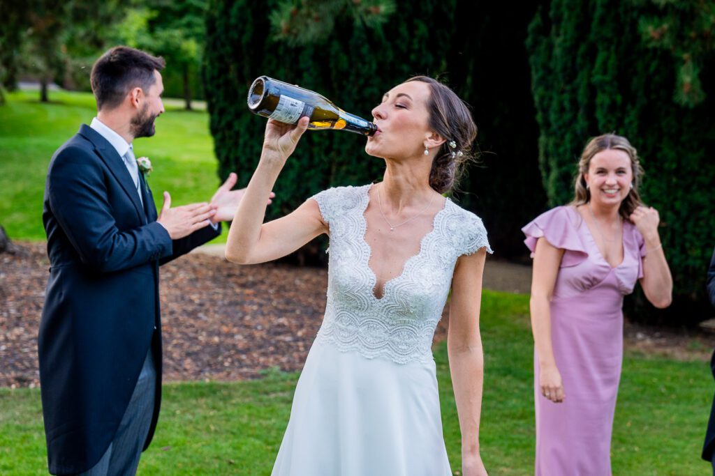 Bride drinking out of a Champagne bottle at the Grove Hotel, Watford. Tim Payne Photography, a Hertfordshire wedding photographer.