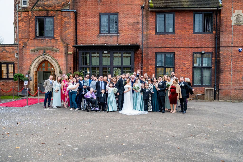Bridal party and guests outside Brickendon Grange wedding venue an imposing red brick manor house