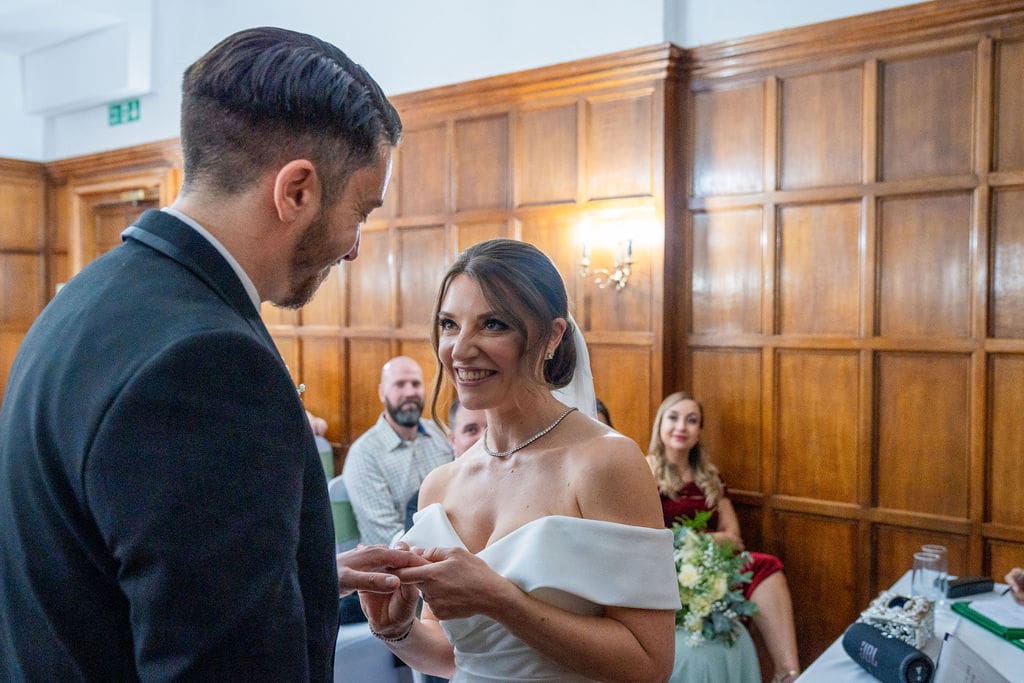 A bride 'squeezing' the wedding ring onto her grooms finger