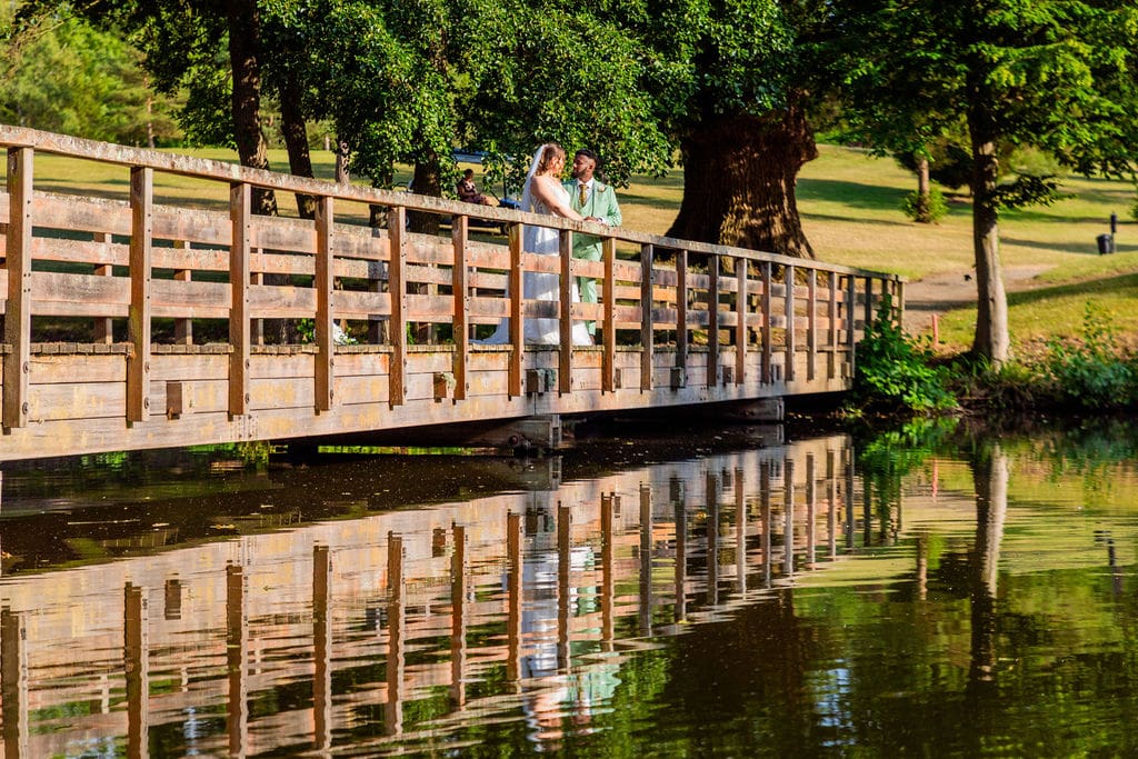 Essendon Country Club wedding venue's long bridge on the golf course, reflected in the water. A bride and groom are embracing on the bridge
