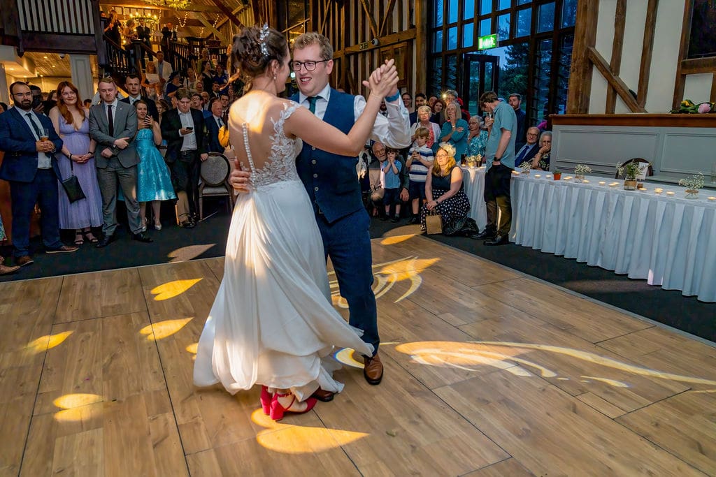 a bride and groom on the dance floor for their first dance as their guests watch on