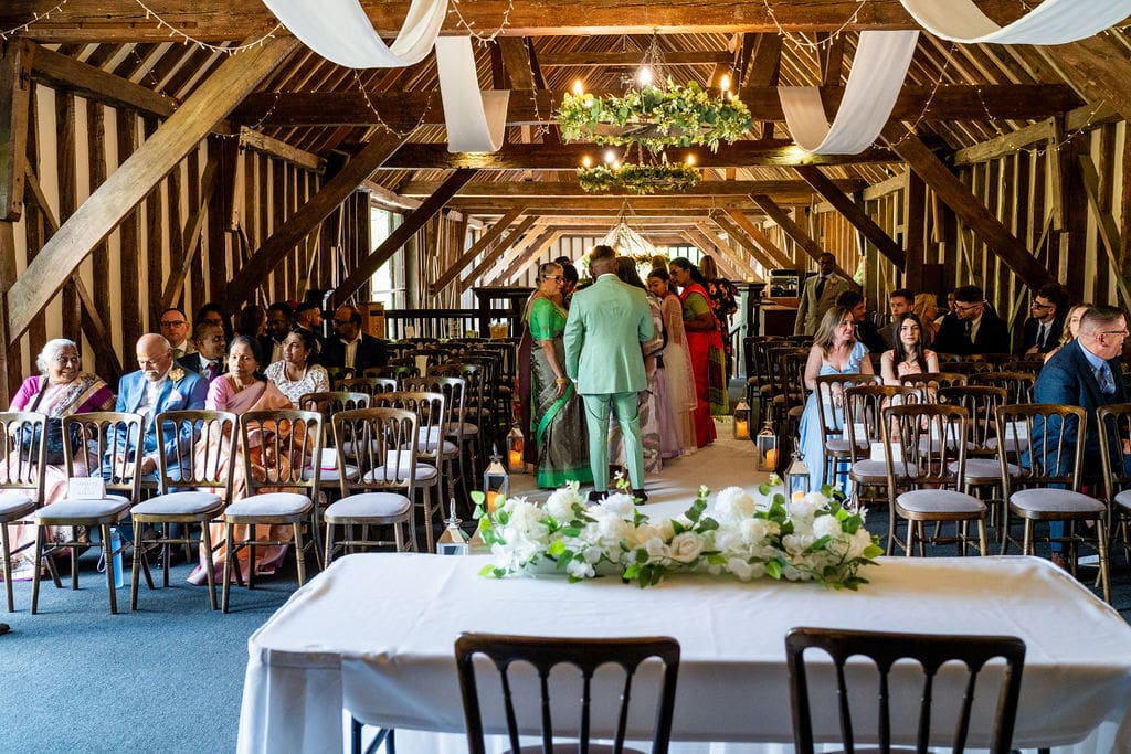 Essendon Country Club wedding venue mezzanine floor set out for a wedding ceremony, dark oak beams are swathed in fabric, the table for signing the register in the foreground with white flowers