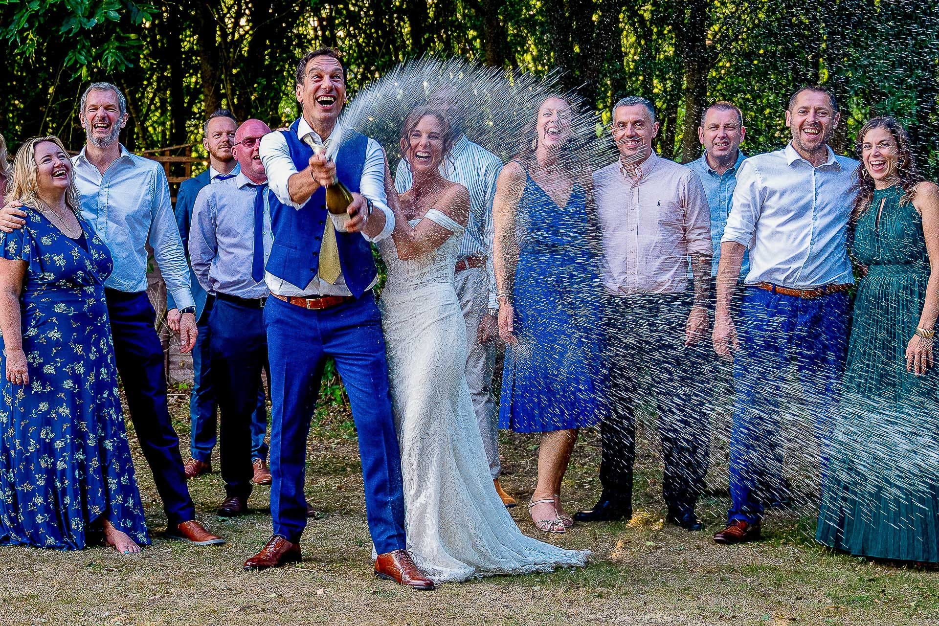 Jon and Sarka spraying a bottle of champagne at the three lakes wedding venue.  A fantastic wedding day expeience   
