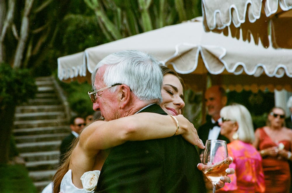 35mm film wedding photography of a bride embracing her father at the wedding reception outside